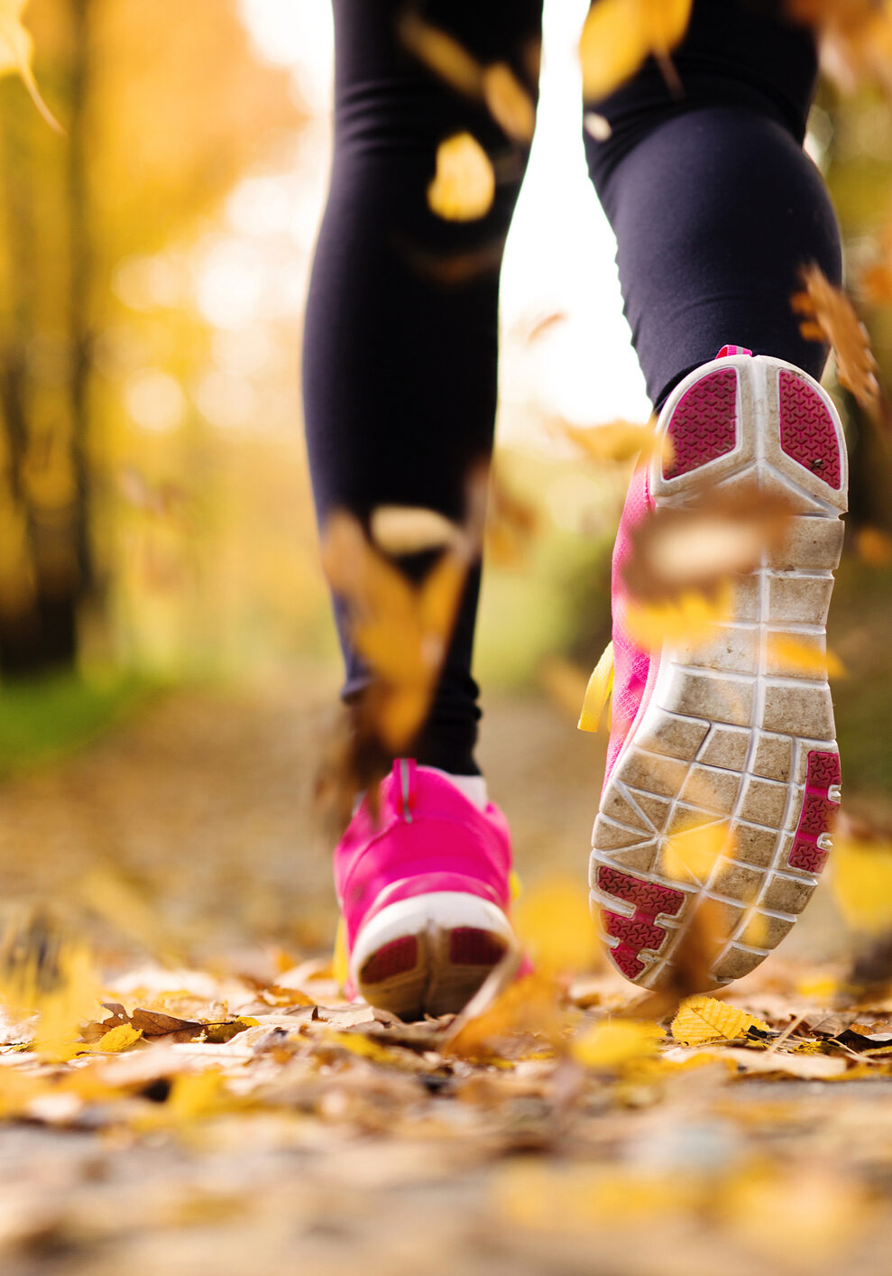 Close up of runner’s feet running in autumn leaves training exercise